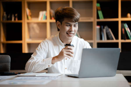 A man sits in the office of a startup company, he is an employee working in the marketing department, planning marketing to grow the company. Concept of working in a startup company office.の写真素材