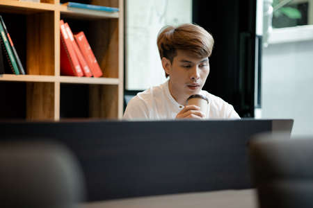 A man sits in the office of a startup company, he is an employee working in the marketing...