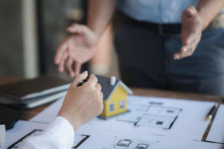 Two architects and engineers are in a meeting to discuss and inspect the house designs to meet the...