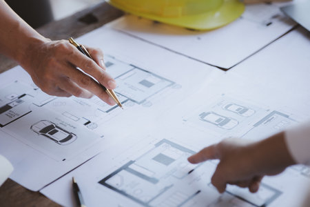 Two architects and engineers are in a meeting to discuss and inspect the house designs to meet the...