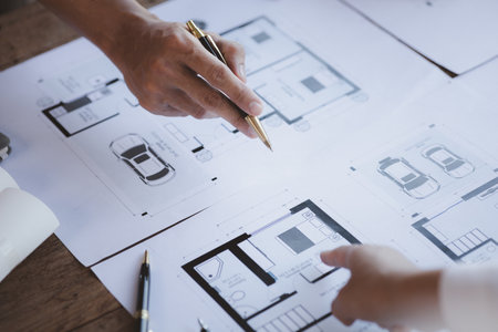 Two architects and engineers are in a meeting to discuss and inspect the house designs to meet the...