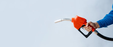 Person holding a gas nozzle on a white background, fuel consumption, petrol-fueled cars, fluctuating oil prices, using alternative fuels for driving.の写真素材