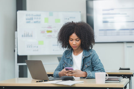 American woman sits in the office of a startup company, she is a company employee, young generation...