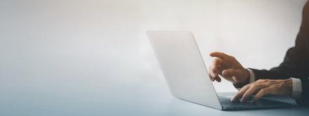Person typing on laptop keyboard and pointing at screen, businessman working on laptop, he is typing messages to colleagues and making financial information sheet to sum up the meeting.の写真素材