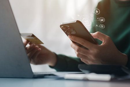 Woman holding a credit card, she uses a credit card to pay for goods and services online, the concept of using a credit card for online shopping, ordering goods and services on the website.の写真素材