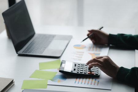 Business woman using a calculator to calculate numbers on a company's financial documents, she is analyzing historical financial data to plan how to grow the company. Financial concept.の写真素材