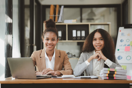 Two American women are working together in the office of a startup company. They are having a brainstorming and planning meeting in a joint department, women leading the way. Concept of women's work.の写真素材