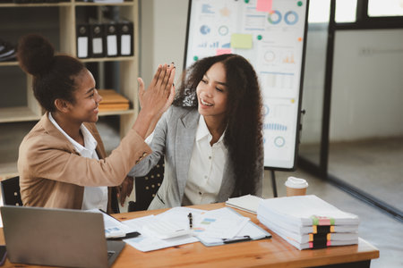Two American women are working together in the office of a startup company. They are having a brainstorming and planning meeting in a joint department, women leading the way. Concept of women's work.の写真素材