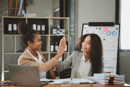 Two American women are working together in the office of a startup company. They are having a brainstorming and planning meeting in a joint department, women leading the way. Concept of women's work.の写真素材