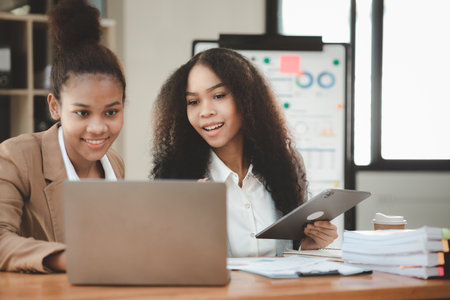 Two American women are working together in the office of a startup company. They are having a brainstorming and planning meeting in a joint department, women leading the way. Concept of women's work.の写真素材