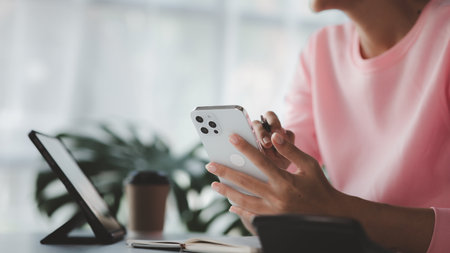 Beautiful Asian woman playing mobile phone in her break from work, she is a marketing manager of a startup company, female leader, supervisor, ceo. Female Leadership Concept.の写真素材