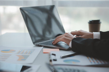 A business man is checking company financial documents and using a laptop to talk to the chief financial officer through a messaging program. Concept of company financial management.の写真素材