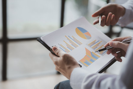Two businessmen pointed to the material for the meeting, working together to plan to develop and solve common business problems. Concept of business management for growth and quality.の写真素材