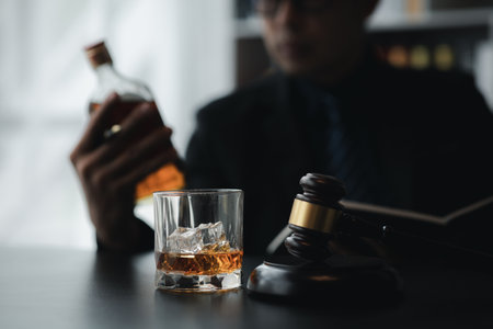A lawyer holding a glass of whiskey, He's in his office, and he's stressing about arguing for a client, he's a lawyer. The concept of clear legal litigation.の写真素材