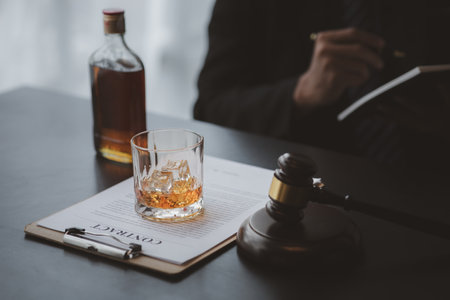 A lawyer holding a glass of whiskey, He's in his office, and he's stressing about arguing for a client, he's a lawyer. The concept of clear legal litigation.の写真素材