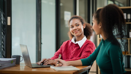 Two American women are working together in the office of a startup company. They are having a...