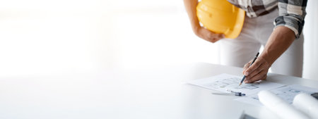 The architect is pointing to the house plans he has designed, he is meeting with engineers and clients to adjust the design before construction starts. Floor plan and interior design concepts.の写真素材