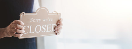 Man holding open/close sign in front of entrance, Goods and Service shop clerk holding sign to notify customers whether the store is open or closed, the opening of the restaurant.の写真素材