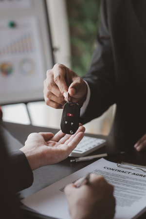 A car rental company employee pointed out the renter to sign the rental agreement after discussing the details and rental terms with the renter. Concept of car rental.の写真素材