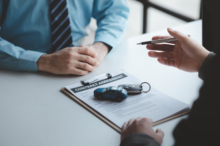 A car salesman is explaining the purchase details and details in the car purchase contract before signing acceptance of the terms, the car sales contract through an agent. Car trading concept.の写真素材
