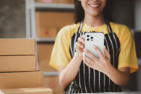 Online store salesperson is writing a customer's shipping address on parcel box before sending it to private carrier for delivery to customer. The idea of opening an online store and packing products.の写真素材