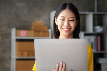 The owner of an online store is checking orders for packaged products in order to prepare them for delivery to customers as ordered through the website. Online selling and online shopping concepts.の写真素材