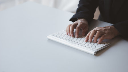 Person typing on a computer keyboard, businessman is working in a startup company's office, he is typing messages to his colleagues and making financial documents summarizing the meetings. Copy space.の写真素材