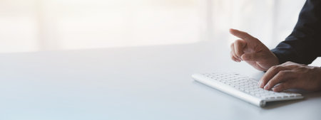 Person typing on a computer keyboard, businessman is working in a startup company's office, he is typing messages to his colleagues and making financial documents summarizing the meetings. Copy space.の写真素材