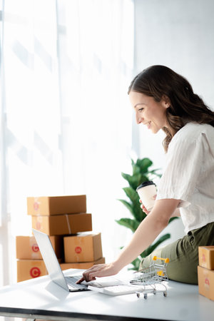 A beautiful business owner opens an online store, she is checking orders from customers, sending goods through a courier company, concept of a woman opening an online business.の写真素材