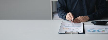 Business man pointing to a pie chart document showing company financial information, He sits in her private office, a document showing company financial information in chart form. Financial conceptsの写真素材
