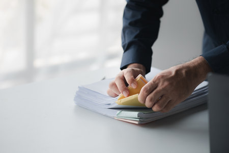 Businessman sorting stacks of department meeting papers, document management in corporate office....