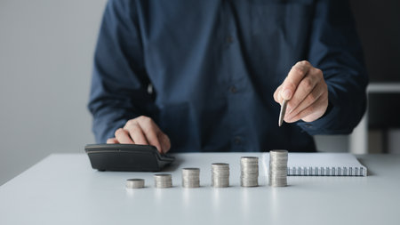 A businessman is keeping a record of his income and expenses, he plans his finances by using his monthly savings to buy funds to make it grow faster. Concept of saving money for investment.の写真素材