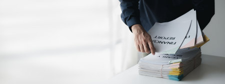 Businessman sorting stacks of department meeting papers, document management in corporate office. Office document management and storage concept.の写真素材
