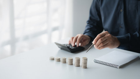 A businessman is keeping a record of his income and expenses, he plans his finances by using his monthly savings to buy funds to make it grow faster. Concept of saving money for investment.の写真素材