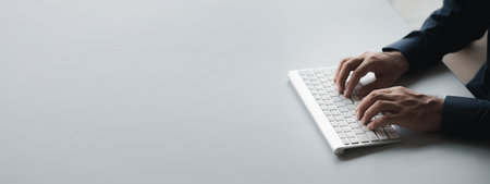 Person typing on a computer keyboard, businessman is working in a startup company's office, he is typing messages to his colleagues and making financial documents summarizing the meetings. Copy space.の写真素材