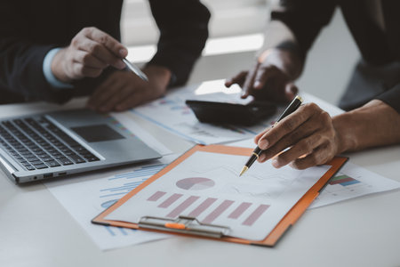 Two businessmen are brainstorming together and reviewing the company financial documents that the finance department has summarized, they are business partners. Business administration concept.の写真素材