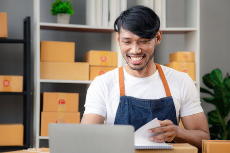 An Asian man owns an online store, he is an internet store operator selling products through an online shopping platform. The concept of selling goods and services on the internet.の写真素材