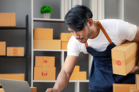 An Asian man owns an online store, he is an internet store operator selling products through an online shopping platform. The concept of selling goods and services on the internet.の写真素材