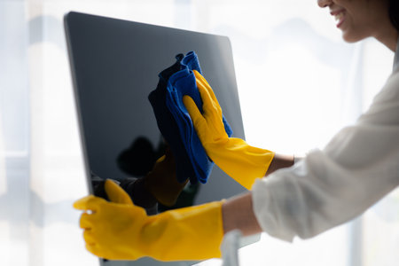 Person cleaning room, cleaning worker is using cloth to wipe computer screen in company office room. Cleaning staff. Concept of cleanliness in the organization.の写真素材