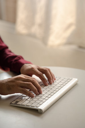 Person typing on a computer keyboard, businessman is working in a startup company's office, he is typing messages to his colleagues and making financial documents summarizing the meetings. Copy space.の写真素材