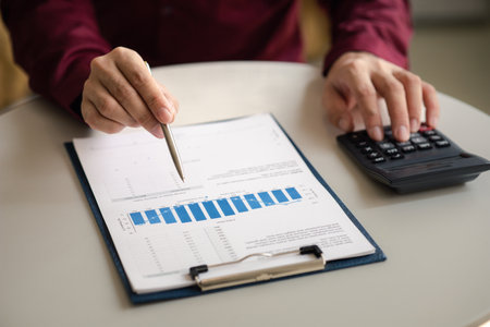 A financier is reviewing company financial documents, monthly financial statement summary from the...