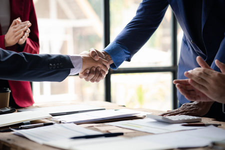 Close-up two business men holding hands, Two businessmen are agreeing on business together and shaking hands after a successful negotiation. Handshaking is a Western greeting or congratulation.の写真素材