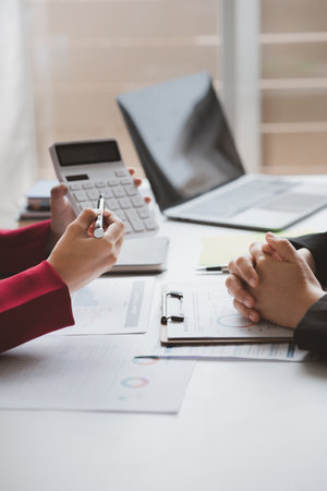 Two businessmen are brainstorming together and reviewing the company financial documents that the...