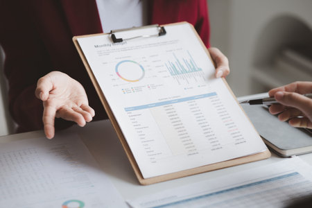 Two businessmen are brainstorming together and reviewing the company financial documents that the...