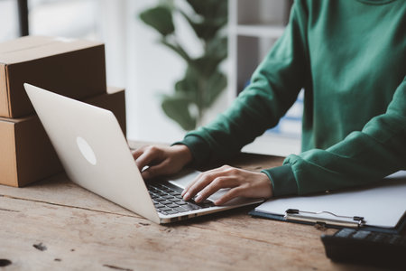 A person is using a laptop. Business owner opens an online store, she is checking orders from customers, sending goods through a courier company, concept of a opening an online business.の写真素材