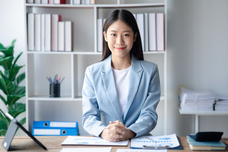 A businesswoman is checking company financial documents and using a tablet to talk to the chief financial officer through a messaging program. Concept of company financial management.の写真素材