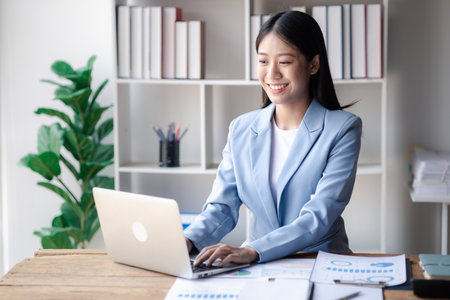 A businesswoman is checking company financial documents and using a tablet to talk to the chief financial officer through a messaging program. Concept of company financial management.の写真素材