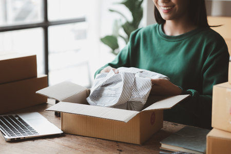 A person is packing parcel boxes according to orders, she owns an online store, she packs and ships through a private transport company. Online selling and online shopping concepts.の写真素材