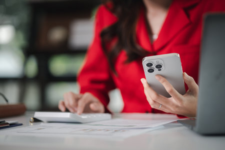 young businesswoman looking at financial information from a mobile phone, she is checking company financial documents, she is a female executive of a startup company. Concept of financial management.の写真素材