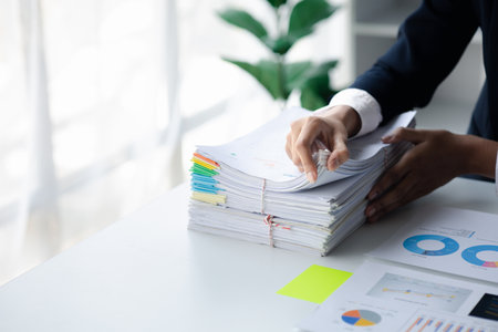 Businessman looking through stacks of papers on desk, corporate financial papers, monthly financial...